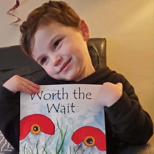 A child holding a book that says "Worth the Wait"